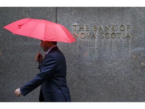 A pedestrian carrying an umbrella walks past the Bank of Nova Scotia headquarters building in Toronto, Ontario, Canada, on Tuesday, April 4, 2017. Scotiabank heads have said that the government may have to impose more measures to cool Toronto's housing market if prices remain "overheated" after the spring buying season. Photographer: Cole Burston/Bloomberg