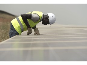 A worker inspects photovoltaic solar panels in an array at the Senergy Santhiou Mekhe PV solar plant in Thies, Senegal, on Monday, Oct. 16, 2017. The electricity produced at the 30 megawatt site, West Africa's largest to date, will be bought by the Senegal National Electricity Company (SENELEC) and injected into the national network. Photographer: Xaume Olleros/Bloomberg