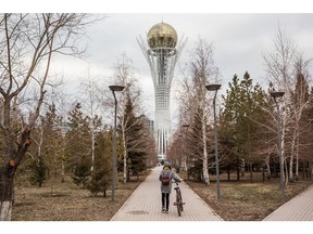 A cyclist wheels a bicycle along a path towards the Bayterak Tower in Astana, Kazakhstan, on Friday, April 13, 2018. Kazakhstan's gross domestic product (GDP) for the first-quarter was 4.1 percent, Kazakhstan's Economy Minister Timur Suleimenov reported to the government on April 16.