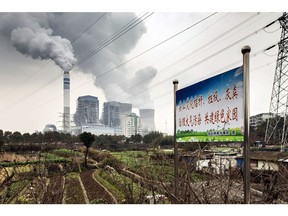 A sign warning local residents not to burn trash in order to reduce pollution stands in a field as emissions rise from cooling towers at a coal-fired power station in Tongling, Anhui province, China, on Wednesday, Jan. 16, 2019. China's economy expanded at its weakest pace since 2009, according to figures Monday, with gross domestic product rising 6.4 percent in the fourth quarter from a year earlier.