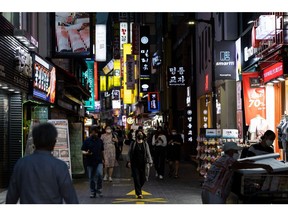 Pedestrians wearing protective masks walk through the Myeongdong shopping district of Seoul at night, South Korea, on Friday, Aug. 20, 2021. Focus is growing on whether the Bank of Korea can take the country's worst-ever virus wave in stride and tighten monetary policy on Aug. 26.