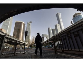 A pedestrian passes buildings in Beijing, China, on Friday, March 4, 2022. China will likely announce its lowest economic growth target in more than three decades when top leaders gather Saturday for a key political meeting, putting pressure on the government to step up fiscal stimulus to spur demand and jobs. Photographer: Qilai Shen/Bloomberg