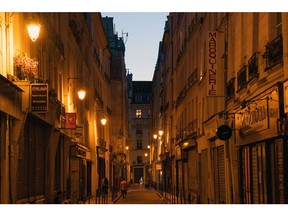 Lit street lamps in a street as the sun fades in Paris.