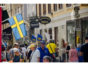 A Swedish national flag hangs from a shop in Gamla Stan, Stockholm. Photographer: Mikael Sjoberg/Bloomberg