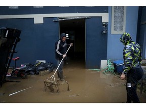 Members of the Nevares remove the mud from their home after La Plata river overflooded and their two-story house was almost completely submerged on September 19, 2022 in Cayey, Puerto Rico.