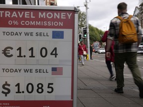 FILE- Pedestrians pass a currency exchange sign outside a shop in London, Sept. 23, 2022. The British pound has resumed a slide against the U.S. dollar that picked up pace last week after the U.K.'s new government outlined plans to cut taxes and boost spending.