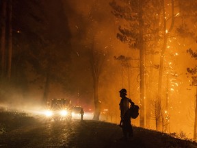 A firefighter monitors the Mosquito Fire as embers swirl in the air near Michigan Bluff in unincorporated Placer County, Calif. Wednesday, Sept. 7, 2022.