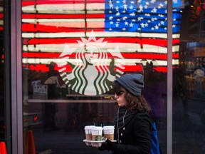 A woman carries coffee out of a Starbucks store in the Manhattan borough of New York.