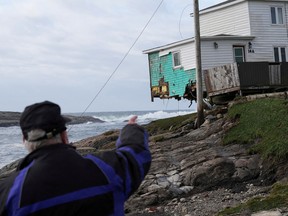 Eine Person zeigt auf ein beschädigtes Haus nach der Ankunft des Hurrikans Fiona in Port Aux Basques, Neufundland.