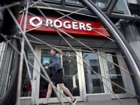 A pedestrian passes in front of a Rogers Communications Inc. store in Toronto.