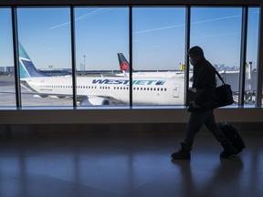 Passengers walk past Air Canada and WestJet planes at Calgary International Airport in Calgary, Alta., Wednesday, Aug. 31, 2022. WestJet flights from Halifax to Montreal will be suspended as of Oct. 28 with several Eastern and Atlantic routes to follow.THE CANADIAN PRESS/Jeff McIntosh