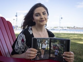 Alyssa Grocutt poses with pictures of her father Kevin who died when she was 11 years old while working at Suncor Energy Inc., in Kingston, Ont., on Wednesday, August 24, 2022.