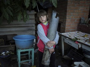 Veronika Tkachenko, 7, holds a piece of a Grad rocket which hit her family's house in the recently retaken town of Izium, Ukraine, Sunday, Sept. 25, 2022.
