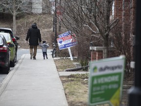 Pedestrians pass in front of a home for sale in the Le Plateau Mont-Royal borough of Montreal, Que.