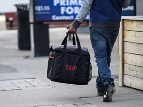 A Skip The Dishes delivery person carrying a food carrier.