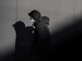 A pedestrian wearing a mask walking on a downtown Toronto street during the COVID-19 pandemic.