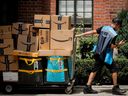 An Amazon.com Inc. delivery worker pulls a delivery cart full of packages in New York City, US