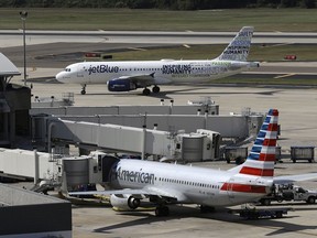 FILE - A JetBlue Airbus A320 taxis to a gate Wednesday, Oct. 26, 2016, after landing, as an American Airlines jet is seen parked at its gate at Tampa International Airport in Tampa, Fla. The government is getting its day in court to try to block a partnership between American Airlines and JetBlue. A trial is scheduled to start Tuesday, Sept. 26, 2022 in the Justice Department's antitrust lawsuit against the airlines.
