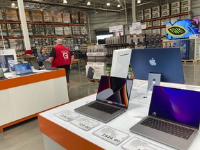 A sales associate helps a prospective customer as laptops sit on display in a Costco warehouse, Aug. 15, 2022, in Sheridn, Colo. Americans picked up their spending a bit in August from July even as surging inflation on household necessities like rent and food take a toll on household budgets. The U.S. retail sales rose an unexpected 0.3% last month, from being down 0.4% in July, the Commerce Department said Thursday., Sept. 15, 2022.