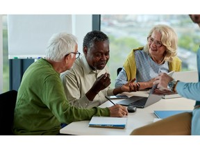 Diverse group of older adults sitting around a laptop