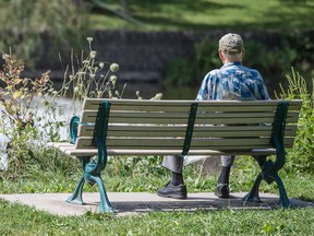 An elderly man sits on a bench by the Humber River in Toronto.
