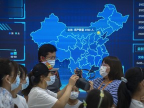 FILE - Visitors wearing face masks prepare to put on a virtual reality headset in front of a digital map of China at a booth at the China International Fair for Trade in Services (CIFTIS) in Beijing on Sept. 3, 2022. China's second largest gaming firm NetEase has received its first game license in over a year in a possible sign Beijing is gradually easing a crackdown on the industry.