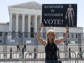 FILE - Nicky Sundt, of Washington, holds a sign with an image depicting Medusa that says, "Remember in November, Vote!," outside of the Supreme Court, June 29, 2022, in Washington. Democrats are pumping an unprecedented amount of money into advertising related to abortion rights, underscoring how central the message is to the party in the final weeks before the November midterm elections.