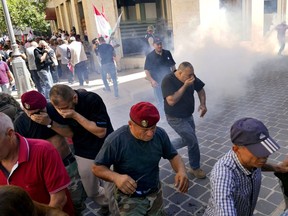 Retired members of the army run from tear gas fired by riot police near the parliament as the legislature was in session discussing the 2022 budget, during a protest in downtown Beirut, Lebanon, Monday, Sept. 26, 2022. The protesters demanded an increase in their monthly retirement pay, decimated during the economic meltdown.