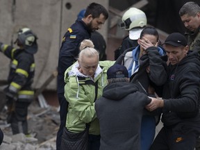 Relatives and friends comfort a woman after Ukrainian rescue workers found a body of a person under the debris following a Russian attack that heavily damaged a school in Mykolaivka, Ukraine, Wednesday, Sept. 28, 2022.