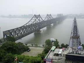 FILE -Visitors walk across the Yalu River Broken Bridge, right, next to the Friendship Bridge connecting China and North Korea in Dandong in northeastern China's Liaoning province, Sept. 9, 2017. North Korea and China resumed freight train service Monday, Sept. 26, 2022, following a five-month hiatus, South Korean officials said, as the North struggles to revive an economy battered by the pandemic, U.N. sanctions and other factors.