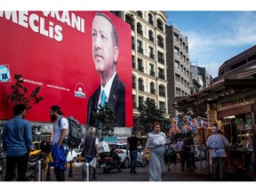 People walk past an election poster showing the portrait of Turkey's President Recep Tayyip Erdogan in Istanbul. Photographer: Chris McGrath/Getty Images