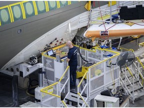 A worker inspects an Airbus A220 plane at the Airbus Canada LP assembly and finishing site in Mirabel, Quebec, Canada, on Wednesday, Nov. 17, 2021. Air Lease Corp. is seeing demand for single-aisle jets like Airbus SE's A320neo and A220 families outstrip the planemakers' current rates of manufacturing.