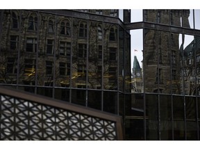 The Peace Tower is reflected in a window at the Bank of Canada.