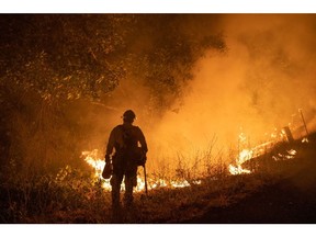 A firefighter holds a drip torch along Michigan Bluff Road during the Mosquito Fire near Foresthill, California, US, on Wednesday, Sept. 7, 2022. A wildfire burning in the Tahoe National Forest exploded Wednesday afternoon prompting evacuation orders near Foresthill.