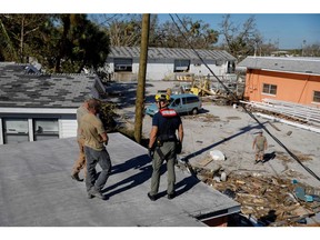 First responders walk on the debris of a house at the marina at San Carlos Maritime Park following Hurricane Ian in Fort Myers, Florida, US, on Friday, Sept. 30, 2022. Two million electricity customers in Florida remained without power Friday morning, according to the tracking site poweroutage.us.