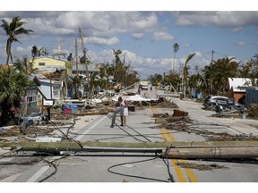 A resident walks past debris on Pine Island Road following Hurricane Ian in Matlacha Isles, Florida, on Oct. 1. Photographer: Eva Marie Uzcategui/Bloomberg