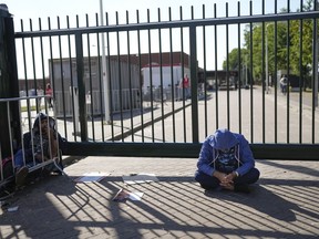 FILE - A man sits outside the gate of an overcrowded asylum seekers center where hundreds of migrants seek shelter in Ter Apel, northern Netherlands, Thursday, Aug. 25, 2022. A Dutch court on Thursday, Oct. 6, 2022 ordered the government and its asylum seeker accommodation agency to significantly improve conditions at overcrowded and unsanitary emergency migrant housing facilities.