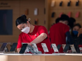 An employee cleans iPhones at an Apple Store in San Francisco.