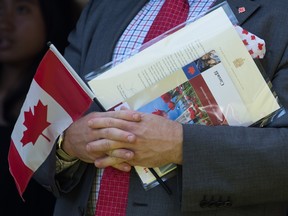 A new Canadian holds a Canadian flag, their citizenship certificate and a letter signed by Prime Minister Justin Trudeau at a citizenship ceremony in 2019.