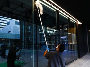 A sign board displays the TSX level as a custodian cleans windows in the financial district in Toronto on Wednesday, September 29, 2021.