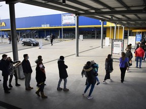 FILE - People wearing protective face mask line up in a queue outside the Swedish furniture giant Ikea shop the last day of the opening of non-essential shops during the coronavirus disease (COVID-19) outbreak, in Aubonne, Switzerland, Saturday, January 16, 2021. Swedish home furnishings giant IKEA said Thursday that despite "unprecedented challenges" caused by the war in Ukraine, supply chain disruptions, increased inflation and lingering fallout from the COVID-19 pandemic, 2022 had been an "exceptional year".