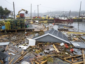 Heavy machinery clears washed-up buildings and rubble in the harbour in Burnt Island, Newfoundland and Labrador, on Tuesday, Sept. 27, 2022. An initial estimate by Catastrophe Indices and Quantification Inc. suggests hurricane Fiona did $660 million in insured damage.