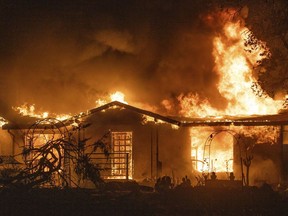 FILE - A house burns on Platina Road at the Zogg Fire near Ono, Calif., on Sep. 27, 2020. California utility regulators on Tuesday, Oct. 25, 2022, proposed penalizing Pacific Gas & Electric more than $155 million in fines for its role in starting the 2020 Zogg Fire in Shasta County that destroyed hundreds of homes and left four people dead.