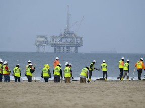 FILE - Workers in protective suits clean the contaminated beach at Huntington Beach, Calif., on Oct. 11, 2021, following a pipeline rupture that spilled tens of thousands of gallons of crude oil off the Southern California coast. The U.S. Army Corps of Engineers granted the approval Friday, Sept. 30, 2022, to Amplify Energy Corp. to repair the pipeline. The Houston company pleaded guilty to federal charges last month of negligently discharging oil.