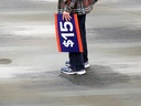 A protester holds a sign calling for a $15 an hour minimum wage. Many in the labour movement now say that is not enough to help workers cope with the rising costs of living.