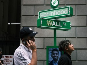 People wait in line for T-shirts at a pop-up kiosk for the online brokerage Robinhood along Wall Street after the company went public with an IPO on July 29, 2021 in New York City.