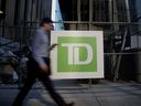 A commuter walks past Toronto-Dominion Bank signage in Toronto's financial district.