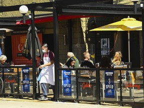 People sit on the outdoor patio at a restaurant in Toronto on Tuesday, March 30, 2021. A recession in Canada will make consumers more cautious with discretionary spending on things like restaurants and entertainment, experts say.