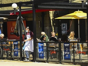 People sit on the outdoor patio of a restaurant in Toronto on Tuesday, March 30, 2021. A recession in Canada will make consumers more cautious with discretionary spending on things like restaurants and entertainment, experts say.