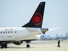 Airline ground crew walks past grounded Air Canada planes as they sit on the tarmac at Pearson International Airport in Toronto on Tuesday, April 27, 2021.